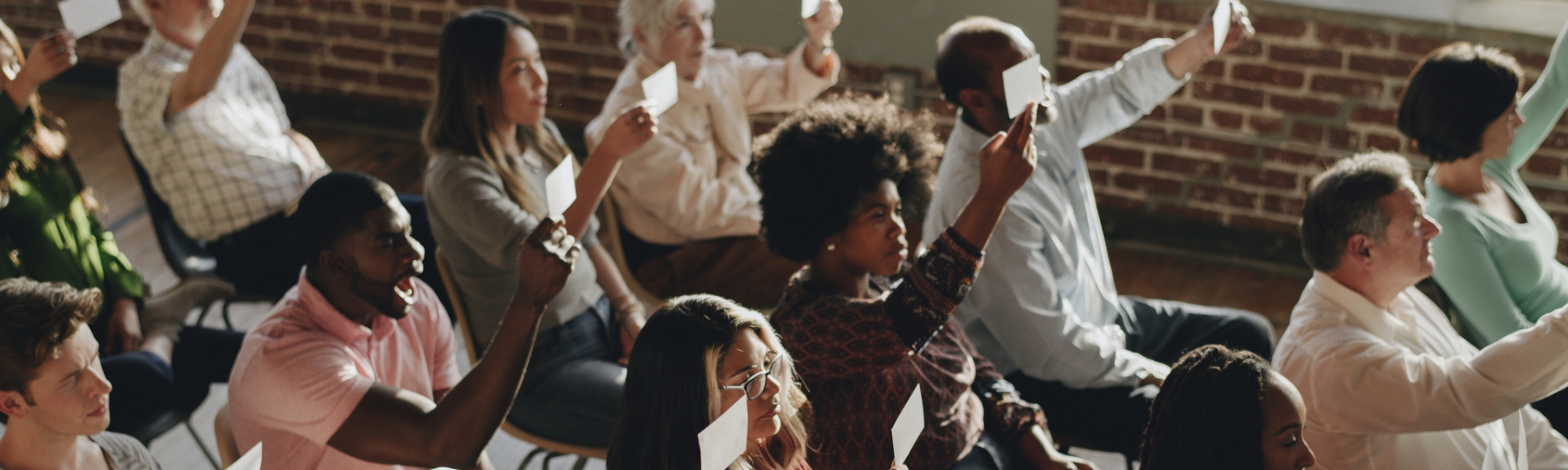 Educators seated in rows holding up response cards during a community building activity